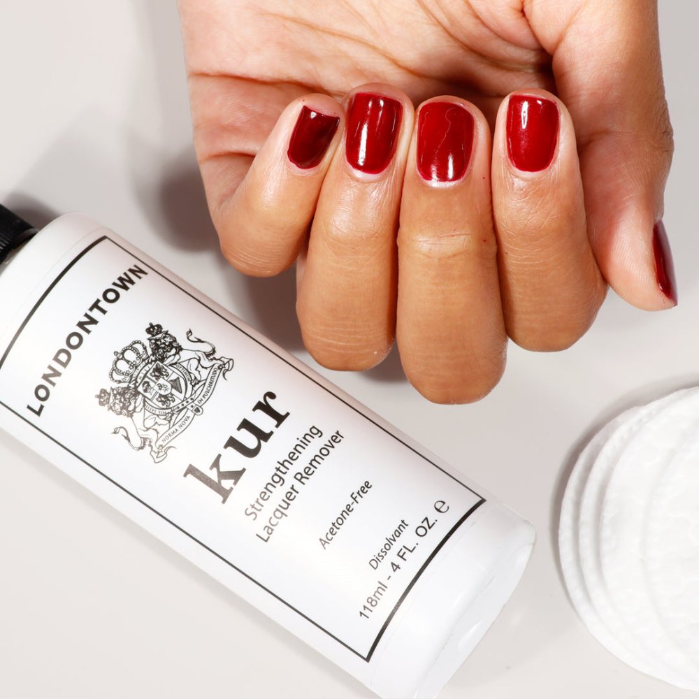 Lahev odlakovače Londontown Strengthening Lacquer Remover vedle nalakovaných nehtů